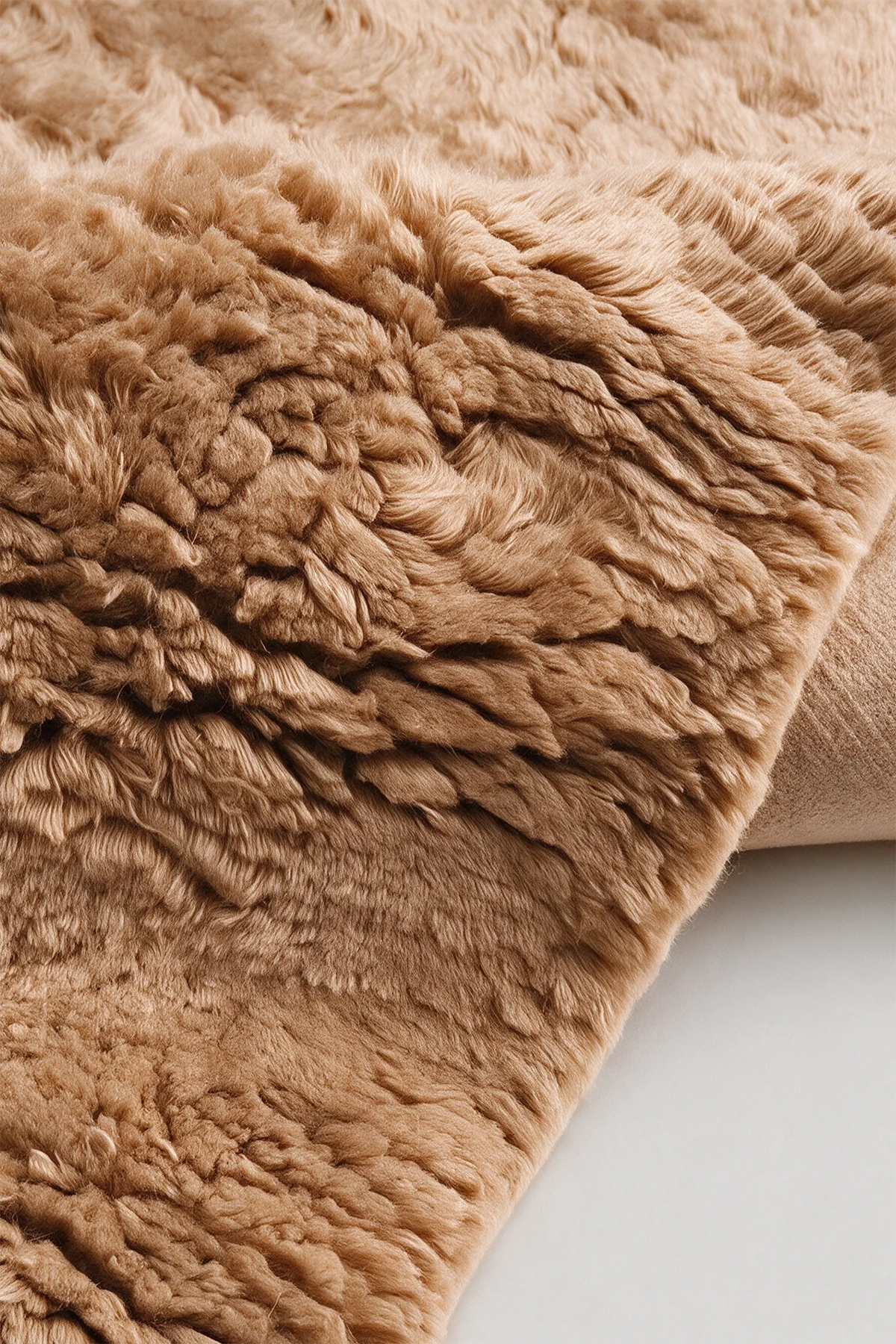 Close-up of the deep camel wool pile on a JUBI hand-knotted shag rug