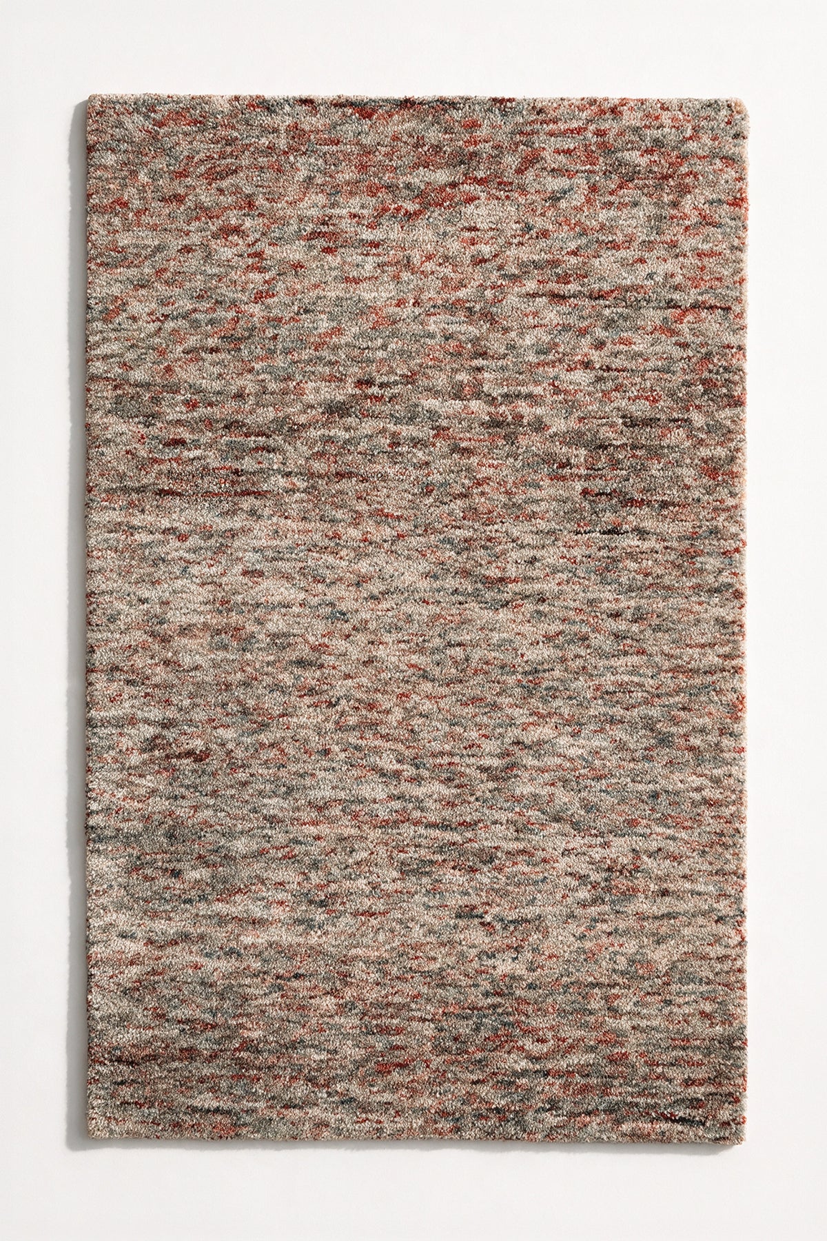 flat lay of a canyon strata hand-tufted wool rug, blended rust red, rose and cream yarns