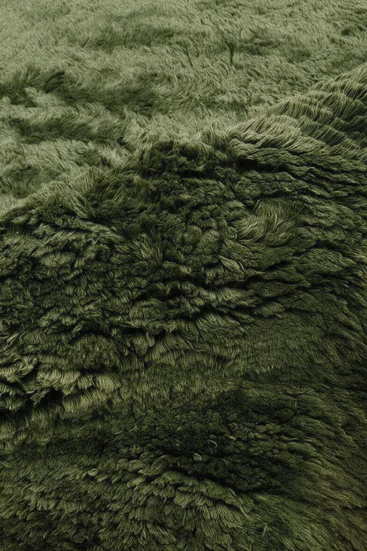 Close-up of the deep dark olive green wool pile on a JUBI hand-knotted shag rug