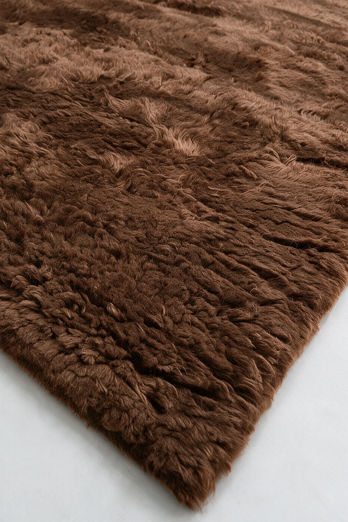 Close-up of the deep umber brown wool pile on a JUBI hand-knotted shag rug
