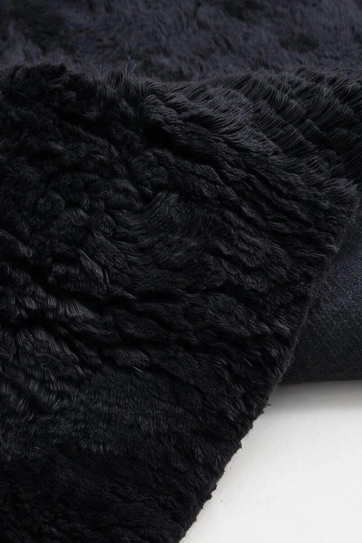 Close-up of the deep black wool pile on a JUBI hand-knotted shag rug