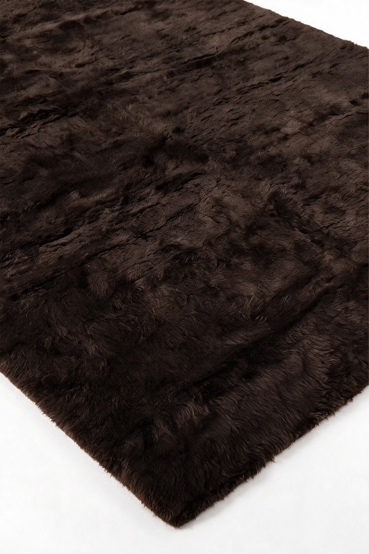 Close-up of the deep chocolate brown wool pile on a JUBI hand-knotted shag rug