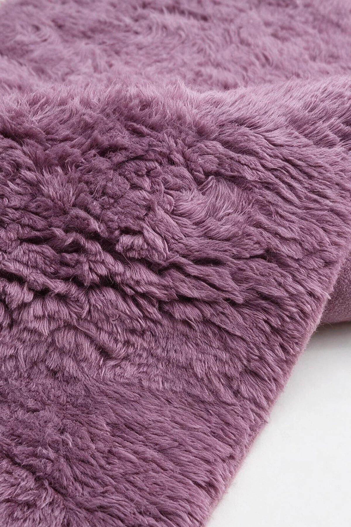 Close-up of the deep mauve wool pile on a JUBI hand-knotted shag rug