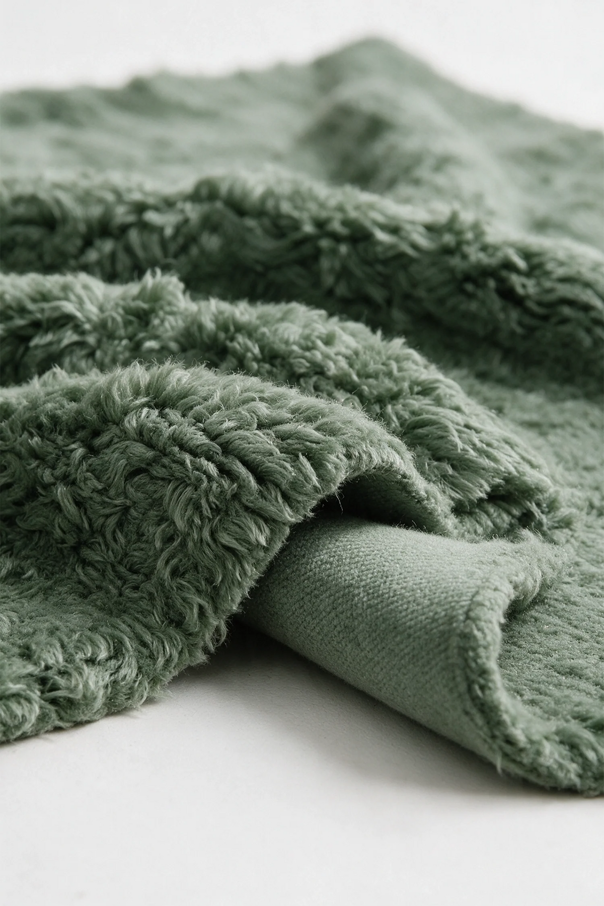 Close-up of the deep sage green wool pile on a JUBI hand-knotted shag rug